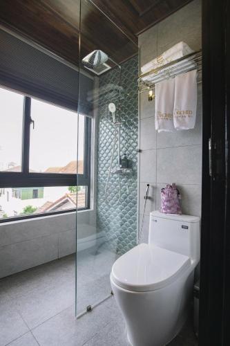 a bathroom with a toilet and a glass shower at The ORCHID PREMIUM Hotel in Hue