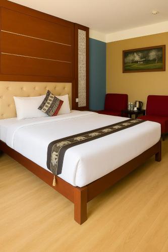 a bedroom with a large white bed and red chairs at Sapa Elegance Hotel in Sa Pa