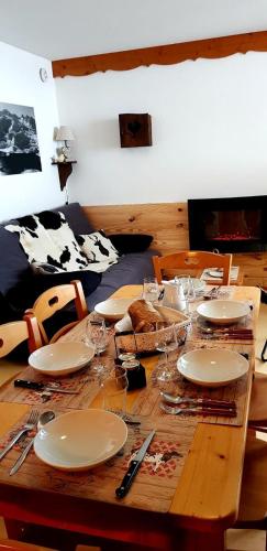 a wooden table with plates and wine glasses on it at Balcons B 011 - PARC NAT VANOISE appart 6 pers in Val Cenis