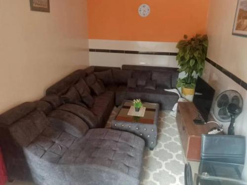 a living room with a brown couch and a table at Spacious Apartment with Pool in M'bour - 100 m² in Mbour