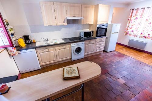 - une cuisine avec des appareils blancs et une table en bois dans l'établissement La Sellerie, à Cour-Cheverny