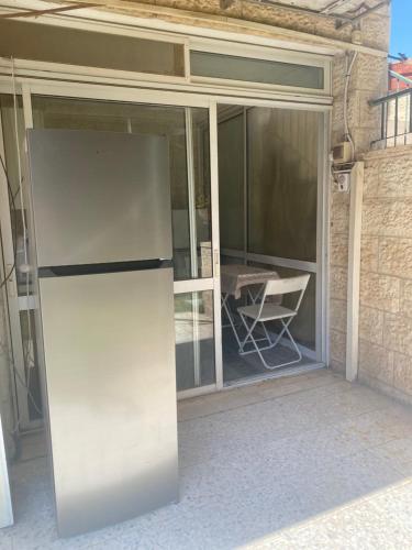 an open sliding glass door with a white refrigerator outside at דירת גן מרווחת במיקום מעולה עם נטפליקס חינמי in Ma'ale Adumim