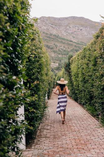 a woman in a hat walking down a brick road at La Paris Estate in Franschhoek