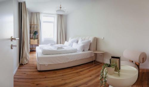 a white bedroom with a white bed and wooden floors at Charmantes Apartment in perfekter Lage mit kostenlosem Parken in Celle
