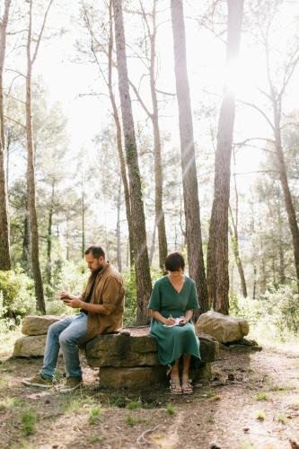 a man and a woman sitting on a stone bench in the woods at La Garriga de Castelladral in Castelladral