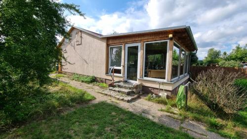 a small house with a large window in a yard at Bungalow Helga in Fürstenwalde