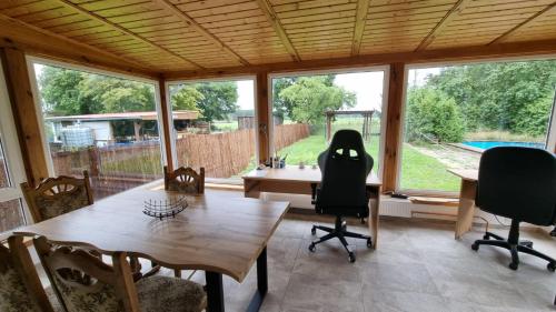 a dining room with a table and chairs and windows at Bungalow Helga in Fürstenwalde