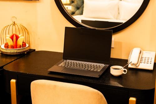a laptop computer on a desk with a phone and a mirror at San Hotel & Spa in Hanoi