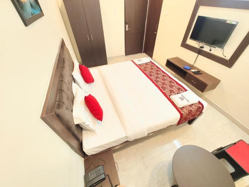 a bedroom with a bed with red pillows and a television at MG Park in Chennai