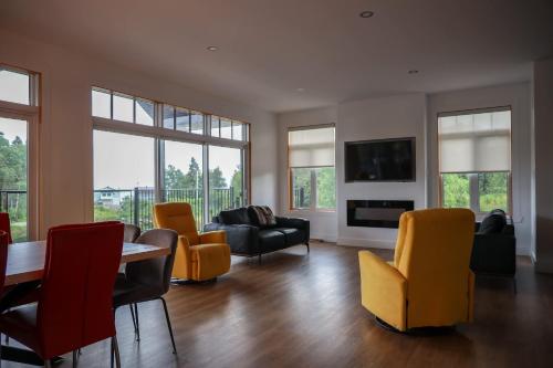 a living room with a table and yellow chairs at Entre lac et Fleuve - Nature & Comfort in Saint-Siméon