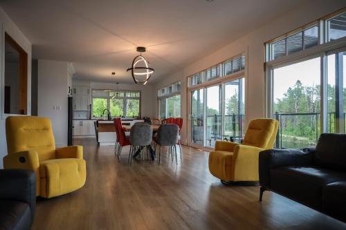 a living room with yellow chairs and a table at Entre lac et Fleuve - Nature & Comfort in Saint-Siméon