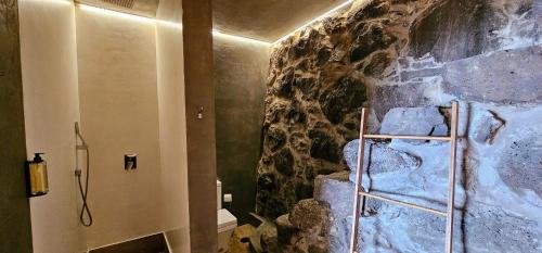 a bathroom with a stone wall with a shower at Les Terrasses Suites in Calheta