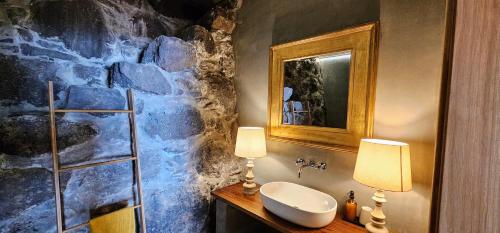 a bathroom with a stone wall with a sink at Les Terrasses Suites in Calheta