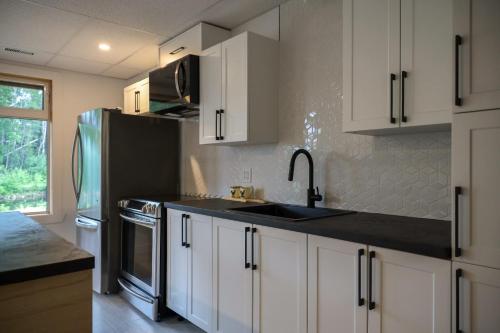a kitchen with white cabinets and a sink and a refrigerator at Entre lac et Fleuve - Nature & Comfort in Saint-Siméon