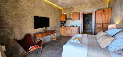 a bedroom with a bed and a desk and a television at Les Terrasses Suites in Calheta