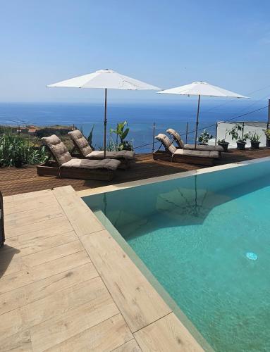 a swimming pool with lounge chairs and umbrellas at Les Terrasses Suites in Calheta