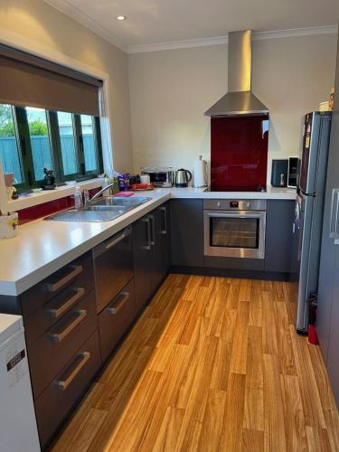 a kitchen with stainless steel appliances and wooden floors at Cosy Cottage in Wellington