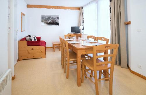 Val CenisにあるBalcons B 015 - PARC NAT VANOISE appart 6 persの木製のテーブルと椅子のあるダイニングルーム