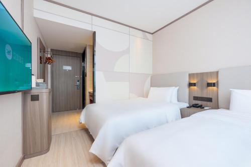 Cette chambre comprend 2 lits et une télévision à écran plat. dans l'établissement Hanting Hotel Beijing Changping Shahe Gonghuacheng, à Pékin