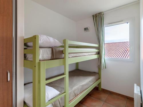 Ce lit superposé vert se trouve dans un dortoir doté d'une fenêtre. dans l'établissement Superbe appartement avec piscine, tennis et accès plage à Saint-Jean-de-Luz - FR-1-239-1108, à Saint-Jean-de-Luz