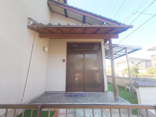 a house with a wooden door and a balcony at 犬山城に近い大人数宿泊が可能で駐車場あり in Inuyama