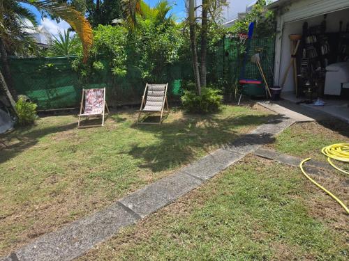 two chairs sitting in a yard with a hose at Maison confortable à Baie-Mahault avec jardin privatif in Baie-Mahault