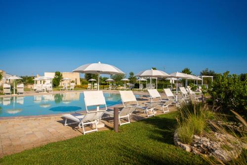 a group of chairs and umbrellas next to a pool at Relais Masseria Le Cesine - CDSHotels in Vernole
