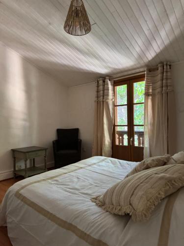 a bedroom with a bed and a chair and a window at chateau Laprade Narbonne in Narbonne