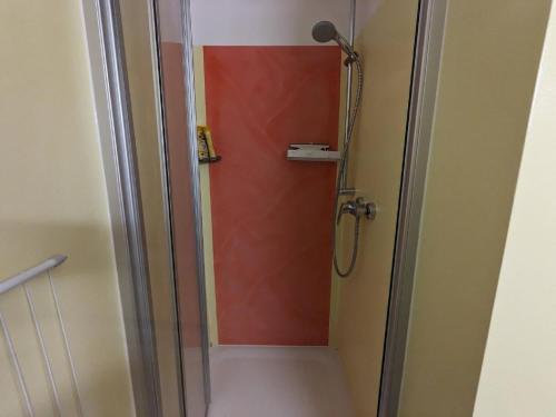 a shower in a bathroom with a red wall at Ferienappartement Bademantelzugang zur Therme in Bad Griesbach