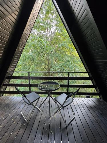 a table and chairs on a wooden deck with a large window at Vila Eden Rudnik in Rudnik Kačerski