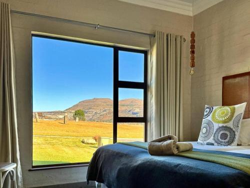 una camera da letto con un letto e una grande finestra di Muirfield Cottages a Clarens