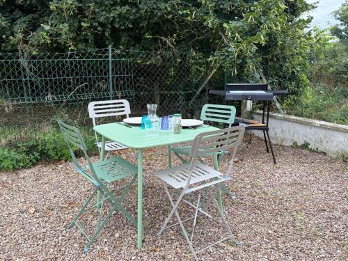 a table with four chairs and a grill with a table and chairsktop at Vert Bocage à Bâlines in Balines