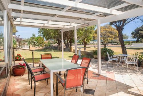 a patio with a table and chairs under a white pergola at Busselton Jetty Heritage House in Busselton