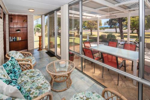 a screened porch with chairs and a table and a table at Busselton Jetty Heritage House in Busselton
