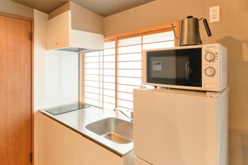 a kitchen with a microwave on top of a refrigerator at Asagaya House in Tokyo