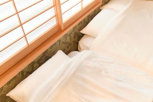 an unmade bed in a room with a window at Asagaya House in Tokyo
