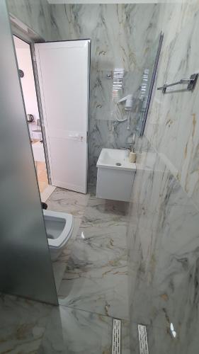 a bathroom with a white toilet and a sink at Vizion Hotel in Shkodër
