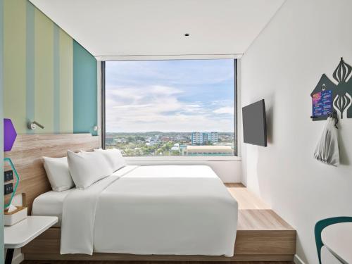 a bedroom with a white bed and a large window at Tru By Hilton Tam Ky City Centre in Tam Ky