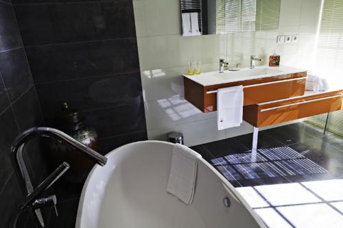 a bathroom with a tub and a sink at Demeures & Châteaux La Belle Meuniere in Royat