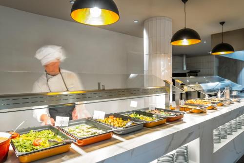 a chef standing in a kitchen preparing food at Hotel Mercury by ALEGRIA in Santa Susanna