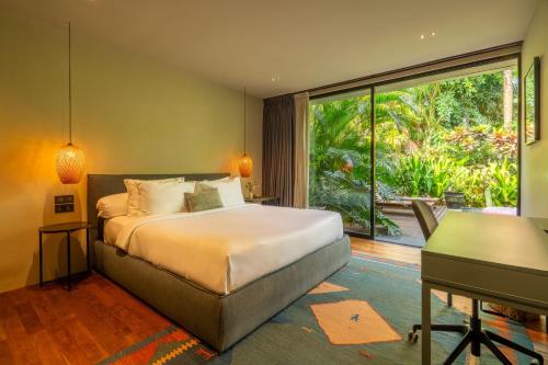 a bedroom with a bed and a desk and a window at Loft 7 Villa by Betterplace in Canggu