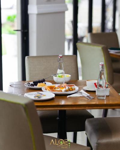 een houten tafel met borden met eten erop bij Aloe Lifestyle Hotel in Eshowe