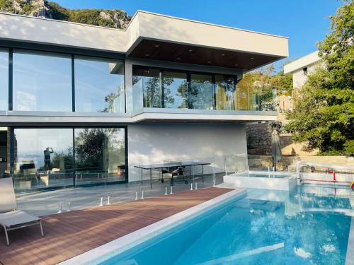 a house with a swimming pool and a table at Luxurious contemporary villa with pool in Brajkovina