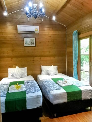 two beds in a room with wooden walls at Sripiamsuk Resort Bangkok in Pathum Thani