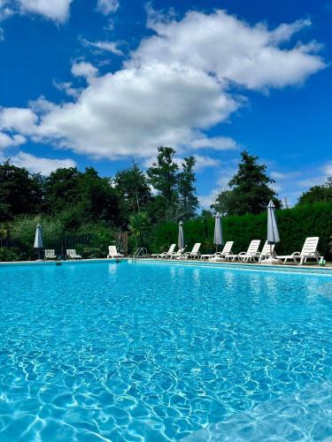 - une piscine avec des chaises et un ciel bleu dans l'établissement Hôtel LES LODGES D'EAUZE, à Eauze