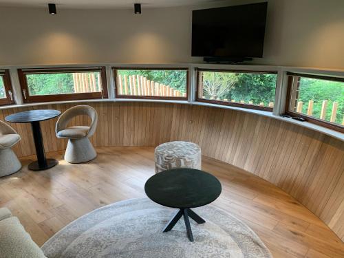 a living room with a tv and a table and chairs at The Nutshell met hottub en sauna | 2 personen in Neede