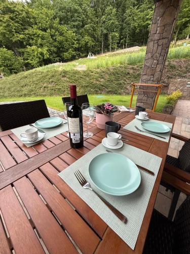 a table with a bottle of wine and plates on it at Apartment House - Oparno 16 in Velemín