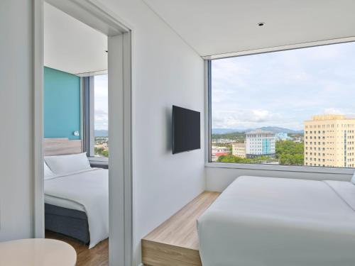 a bedroom with two beds and a large window at Tru By Hilton Tam Ky City Centre in Tam Ky