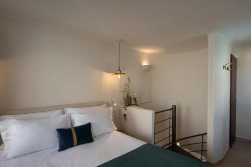 a bedroom with a bed with white sheets and blue pillows at Winery Hotel 1870 in Fira