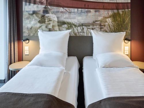 瓦埃勒B&B HOTEL Vejle的酒店房间里的两张床，配有白色枕头